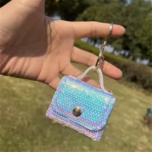 Detail of iridescent sequined mini pouch keychain held against outdoor background.