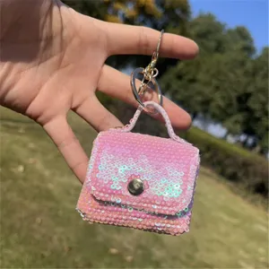 Detailed shot of a pink sequin mini bag keychain held outdoors against a sunny background