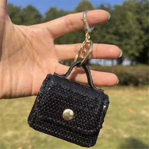 Close-up view of black sequin mini bag keychain with gold hardware and snap button