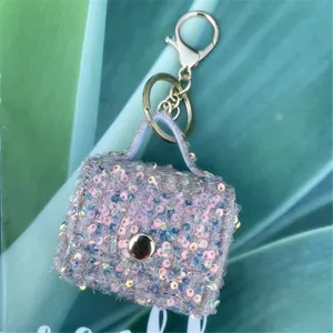 Detailed view of a sparkling pink sequin mini bag keychain charm with golden hardware