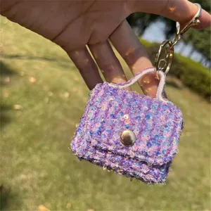 Close-up of a purple sequined mini bag keychain charm held outdoors in natural light.