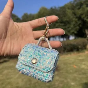 Detailed macro view of an iridescent sequin mini handbag keychain with golden clasp hardware