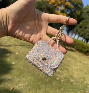 Detailed view of a shimmering pink sequin mini bag keychain earphone pouch held in hand