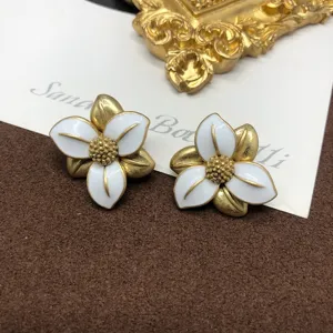 Orecchini a lobo fiore smalto bianco stile vintage con finitura oro invecchiato elegante.