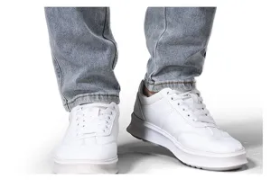 Primer plano detallado de zapatillas blancas informales para hombre con vaqueros azules lavados.