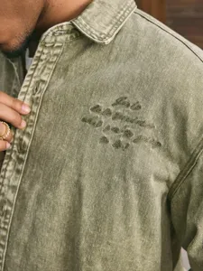 Gedetailleerd overzicht van heren gewassen groene denim jas met stijlvolle borstborduurwerk.
