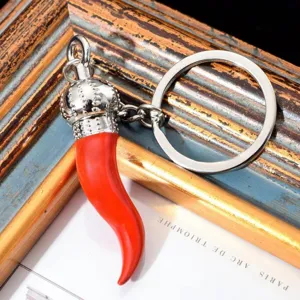 Detailed shot of alloy red pepper keyring with crown top and glossy finish on wooden frame.