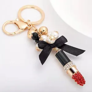 Lipstick keychain detail view featuring a chic black bow, pearls, and sparkling rhinestones.