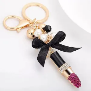 Detailed shot of a stylish lipstick keychain with pearls and black bow, elegant bag charm.