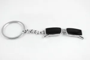 Close-up of creative mini sunglasses keychain metal pendant with smooth black lenses and silver ring.