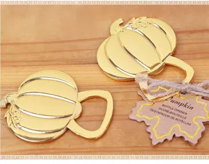 Close-up of a gold pumpkin bottle opener with tag and twine, wedding favor decor.