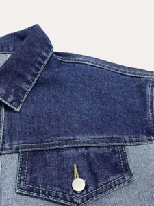 Detail opname van donkerblauwe denim damesjas met kraag en borstzak in klassieke stijl.