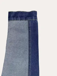 Gedetailleerde close-up van de mouw van een tweekleurige spijkerjas voor dames met stiksels.