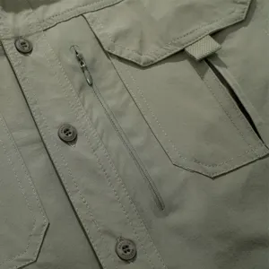 Close-up of men's tactical shirt pocket, button and zipper detail, breathable quick-dry fabric.
