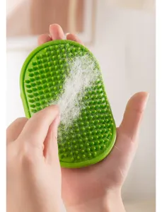 Green silicone pet grooming brush detail view showing removed fur and soft massaging bristles.