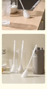 Détail de brosse à biberon en silicone avec tête blanche flexible et long manche pratique.