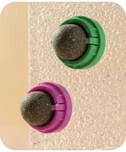 Gros plan détail du jouet balle d'herbe à chat rotative avec base verte et violette pour chats.