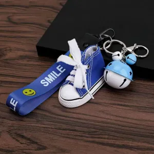Mini blue canvas shoe keychain with cute strap and bell pendant, perfect for car or bag decor.