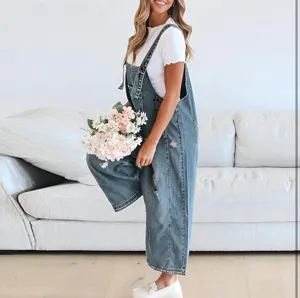 Distressed denim overalls detail showing ripped texture, loose fit and casual style.
