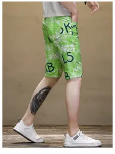 Detail view of men green tie-dye printed casual beach shorts, showing fabric and letter print.