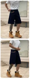 Trendy blue loose denim shorts with colorful embroidery details, casual five-quarter pants style.