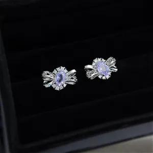 Vue detaillee de jolies boucles doreilles noeud en zircone violette sur velours noir.
