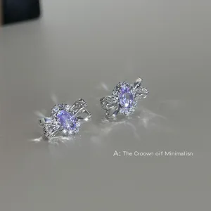 Gros plan des boucles d'oreilles nœud creux en zircon violet élégant avec des pierres scintillantes.