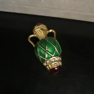 Close-up detail shot of vintage green enamel vase brooch, showing sparkling rhinestones.