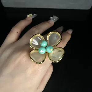 Exquisite vintage floral ring featuring gold-rimmed translucent petals and turquoise center beads.