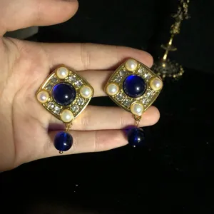 Vintage style diamond and blue glass earrings detail view, elegant retro metal design.