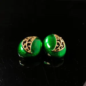 Detailopname vintage groene emaille oorbellen, elegante gouden filigraan, klassieke retro sieraden.