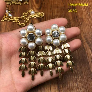 Detailed shot of vintage pearl flower crystal earrings with gold leaf tassels, exquisite design.