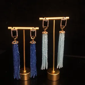 Close-up of long tassel earrings with sparkling rhinestones and colorful glass beads.