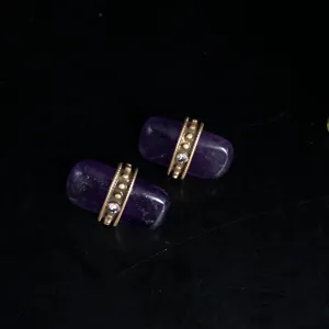 Gros plan sur les détails des boucles d'oreilles vintage en pierre violette et métal or.