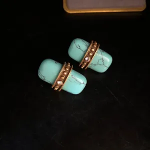 Gros plan de boucles d'oreilles turquoise vintage avec bande métallique dorée et cristal.