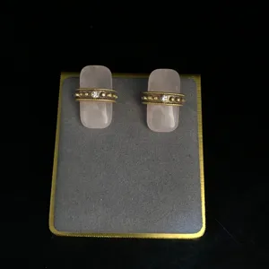 Gros plan de boucles d'oreilles vintage en quartz rose avec bande doree texturee et cristaux.
