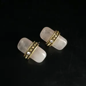 Gros plan détaillé de boucles d'oreilles clous quartz rose avec anneaux bronze.