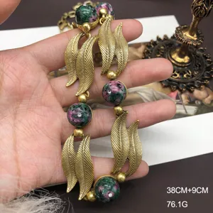 Close-up detail of vintage style gold-tone leaf necklace with green stone beads and 38cm chain.