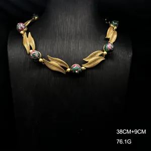 Vintage distressed gold leaf and stone beaded necklace detail shot, elegant antique style jewelry.
