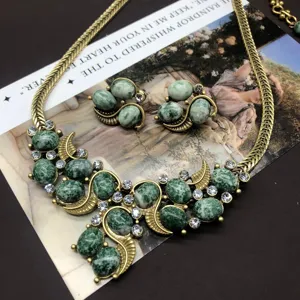 Vintage green stone necklace and earrings set, detailed close-up of retro brass jewelry.