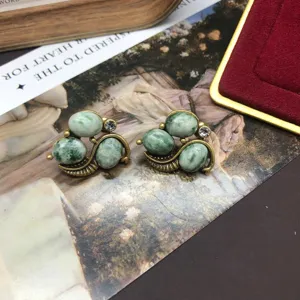 Vintage green stone rhinestone earrings detail view, elegant retro copper metal stud jewelry design.