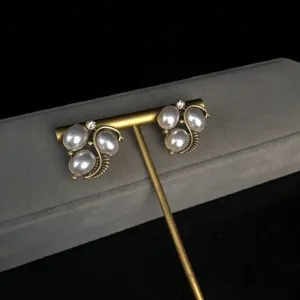 Vintage pearl rhinestone earrings detail shot, elegant bronze metal leaf cluster design jewelry.