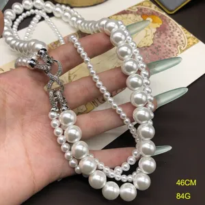 Close-up detail of multi-layer white pearl necklace featuring sparkling rhinestone clasp.