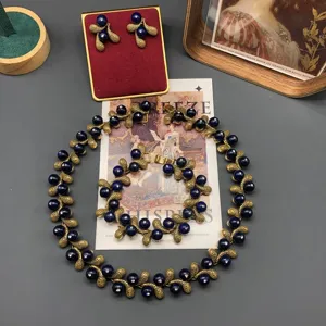 Vintage style jewelry set detail, gold textured leaves with dark blue stones for women.