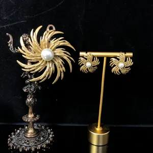 Close-up detail of vintage gold-toned sunburst pearl brooch and earrings set, elegant jewelry.