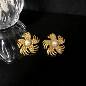 Close-up view of vintage gold swirl pearl earrings, showcasing exquisite detailed texture.