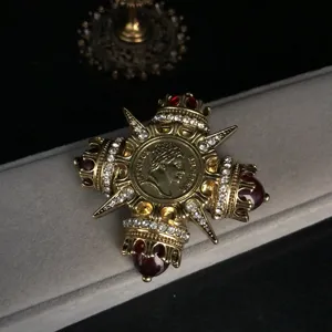 Detailansicht einer vintage-Hof-stil Kreuz Brosche mit Strass und roten Steinen.