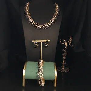 Detail display of vintage gold hollow black gemstone necklace bracelet and earrings jewelry set.