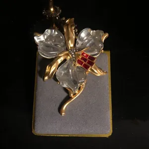 Vue détaillée d'une élégante broche orchidée vintage avec pétales et pierres rouges.