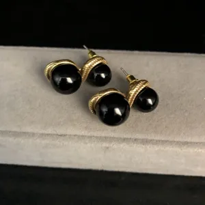Close-up detail of vintage style gold-toned double-bead earrings with black stone inlay.